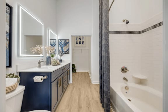 A bathroom with a blue vanity and a white bathtub.