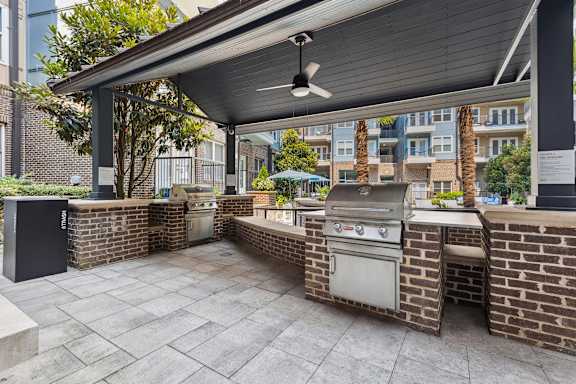 A patio with a grill and a fan.