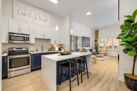 A kitchen with a white island and black bar stools.
