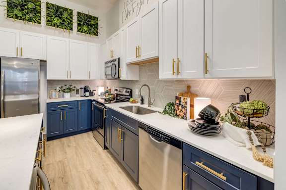 A kitchen with white cabinets and a blue island.