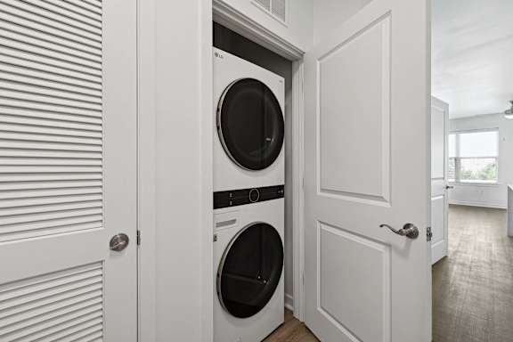 A white door is open to reveal a white washing machine.