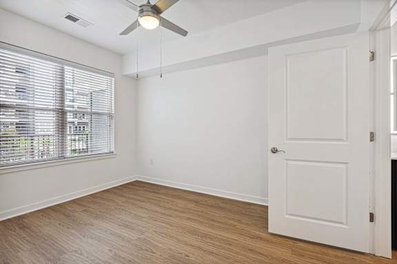A room with a ceiling fan and a door.