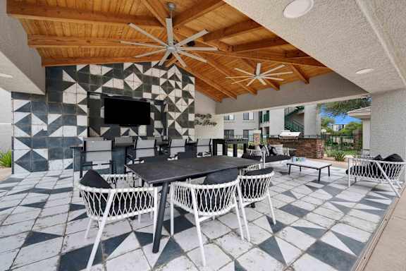 A patio with a table and chairs under a wooden ceiling.