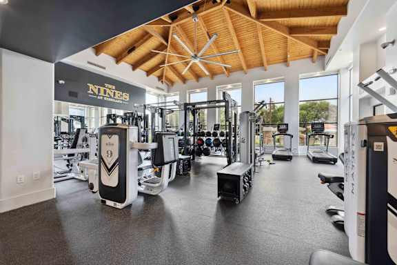 A gym with a variety of equipment including a treadmill, a weight bench and a rowing machine.