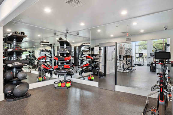 A gym with a variety of equipment including treadmills, weights, and exercise machines.