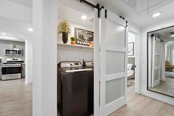 A modern kitchen with a black fridge and white cabinets.
