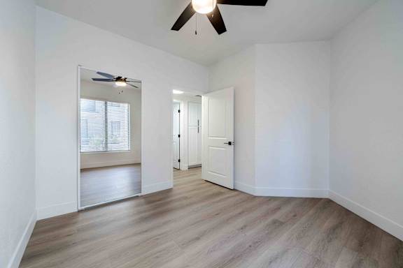A room with a ceiling fan and a door.