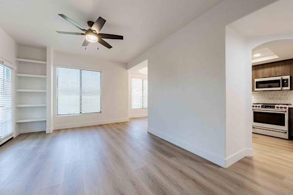 A spacious room with a ceiling fan and a kitchen area with a stove and oven.