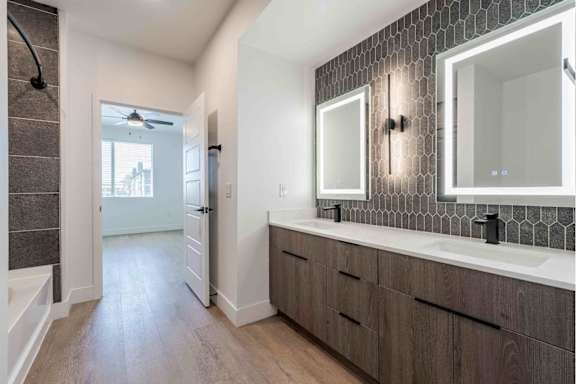 A bathroom with a dark wood floor and white walls.