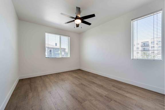 A room with a ceiling fan and wooden flooring.