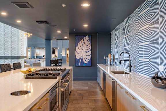 A modern kitchen with a large island and a painting on the wall.