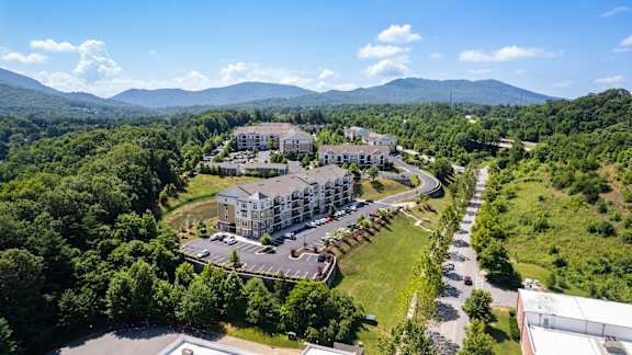 A large building complex surrounded by trees and a parking lot.