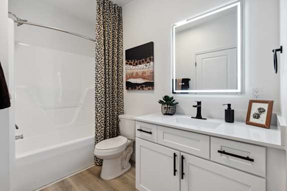 A white bathroom with a toilet, sink, and mirror.