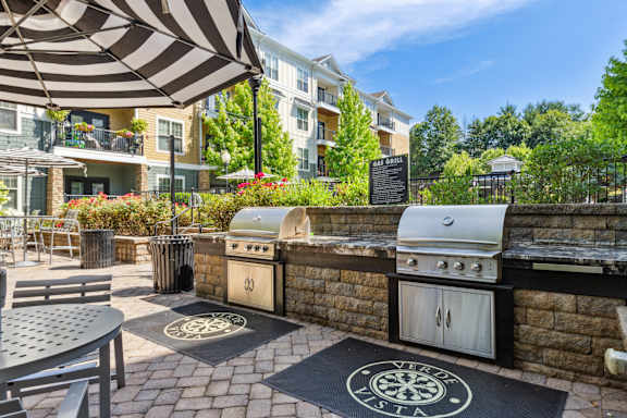 A patio with a grill and umbrella.