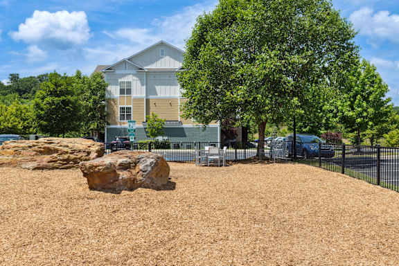 A large rock sits in the middle of a mulched area in front of a house.