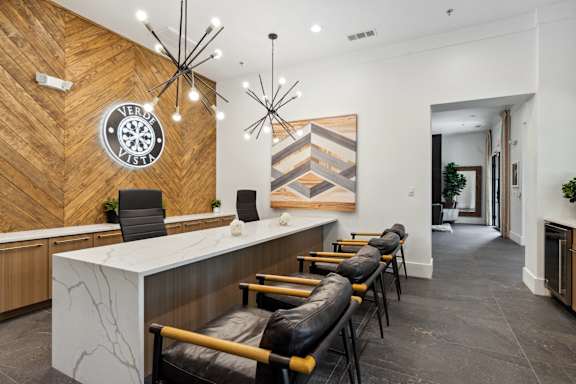 A reception area with a white counter and black chairs.