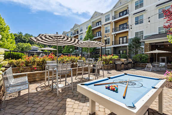 A pool table is set up on a patio with a pool cue and balls on it.
