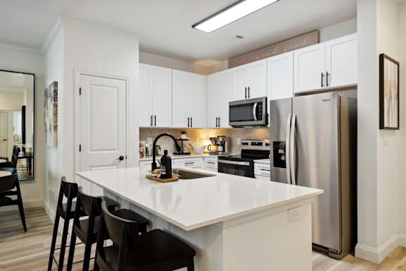 A kitchen with white cabinets and a white island.