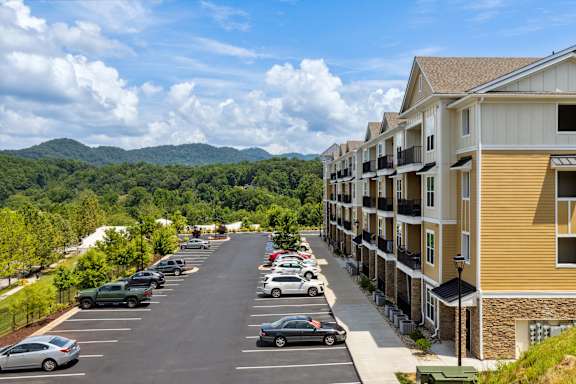 A parking lot with cars and apartment buildings on the side.
