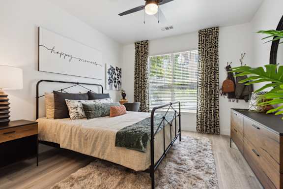 A bedroom with a bed, a ceiling fan, and a rug.