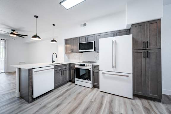 A modern kitchen with a white fridge, microwave, and oven.