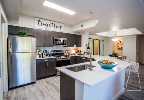 A modern kitchen with a large island and a bowl of food on it.