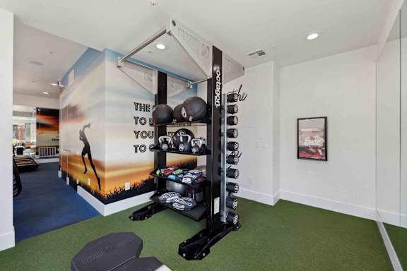 A gym room with a wall mural that says "The way to fitness is through the gym".
