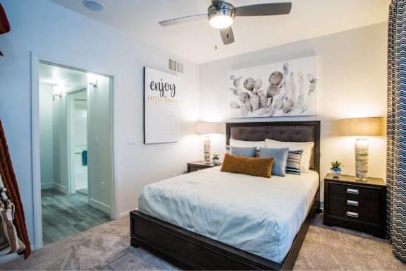 A bedroom with a bed, nightstands, and a ceiling fan.