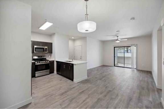 A spacious kitchen with dark wood floors and white walls.
