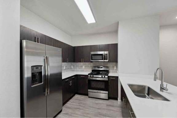 A modern kitchen with a stainless steel refrigerator, oven, and sink.