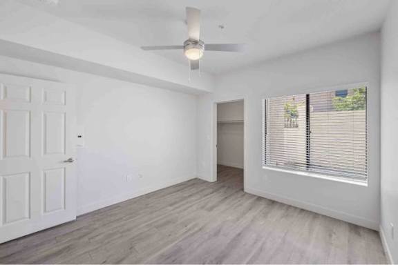A room with a ceiling fan and a window with blinds.