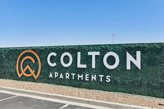 A large green sign with the words Colton Apartments on it.