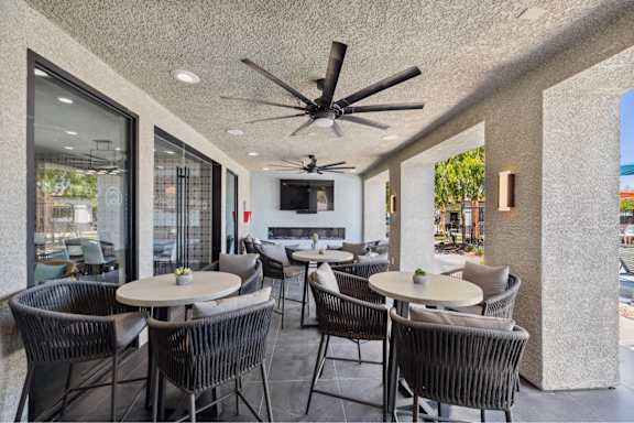 A patio with a table and chairs and a ceiling fan.