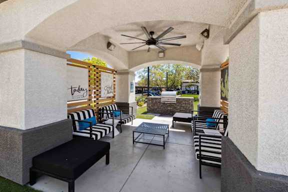 A patio with a black bench and striped chairs.