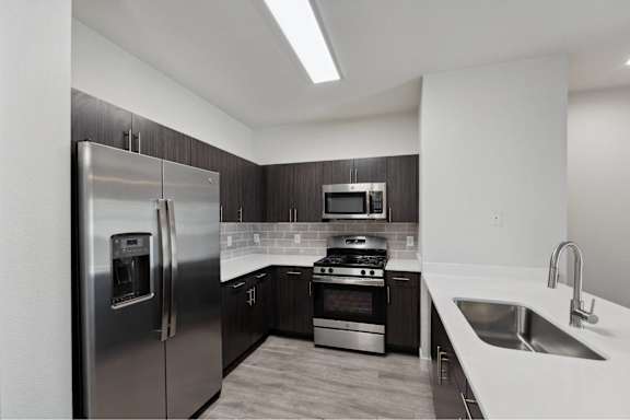 A modern kitchen with a stainless steel refrigerator, oven, and sink.