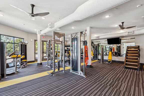 a gym with weights and cardio equipment and a tv on the ceiling