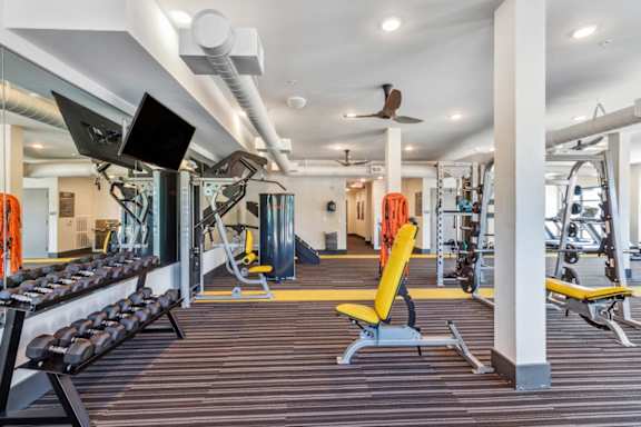 a gym with weights and cardio equipment and a tv