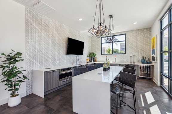 A modern kitchen with a white island and black chairs.