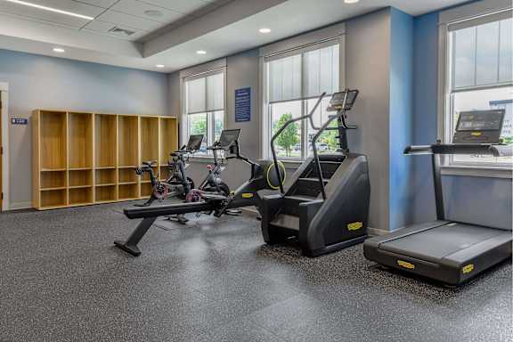 A gym with treadmills, elliptical machines, and a weight rack.