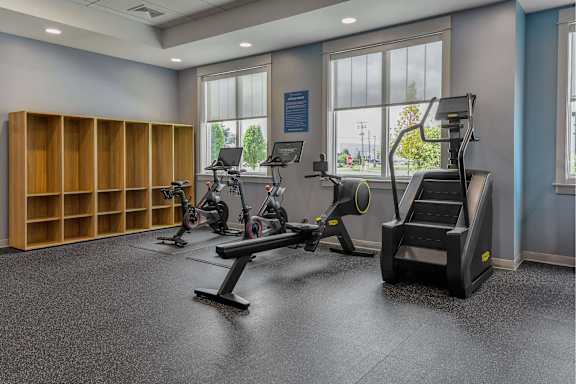 A gym with a variety of equipment including treadmills, weights, and a stair climber.