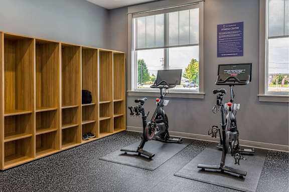 A gym with exercise bikes and wooden storage units.