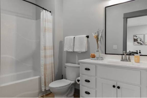 A white bathroom with a toilet, sink, and shower curtain.