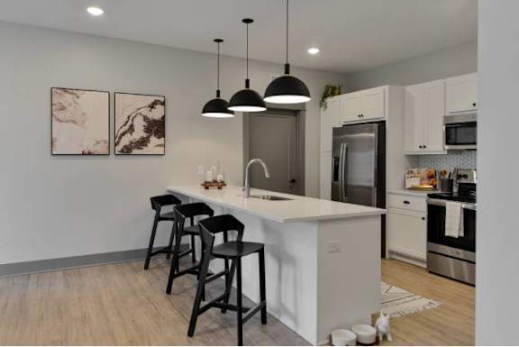 A kitchen with a white island and black bar stools.
