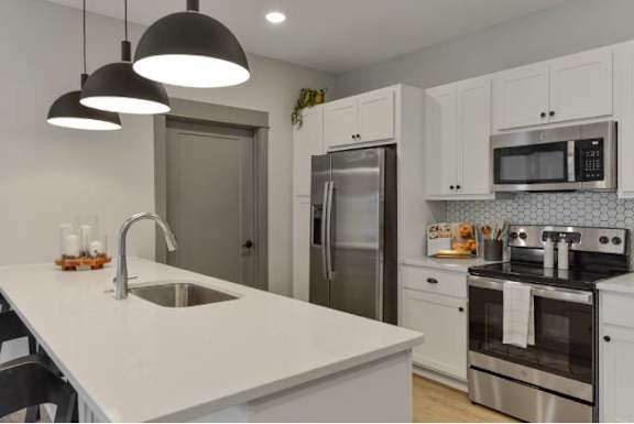 A modern kitchen with a white countertop and stainless steel appliances.