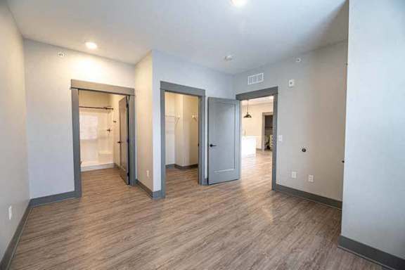 A room with wood flooring and three doors.