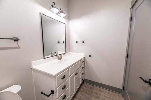 A white bathroom vanity with a mirror and a toilet.