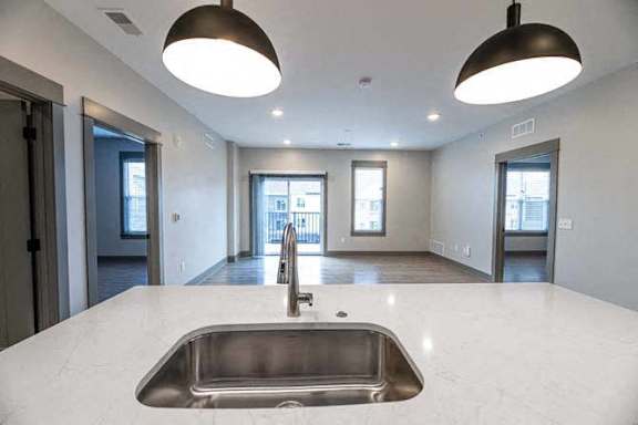 A modern kitchen with a stainless steel sink and pendant lights.