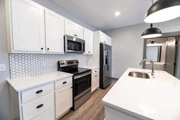 A kitchen with white cabinets and a black stove top oven.