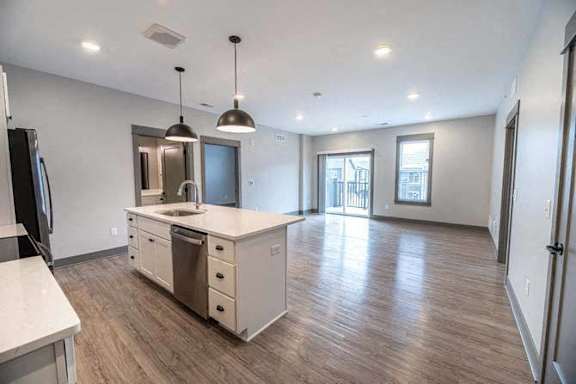 A kitchen with a refrigerator, sink, and cabinets.