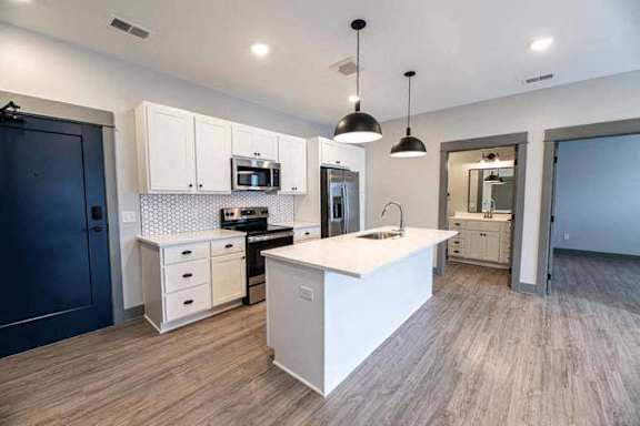 A modern kitchen with a white island and dark blue door.
